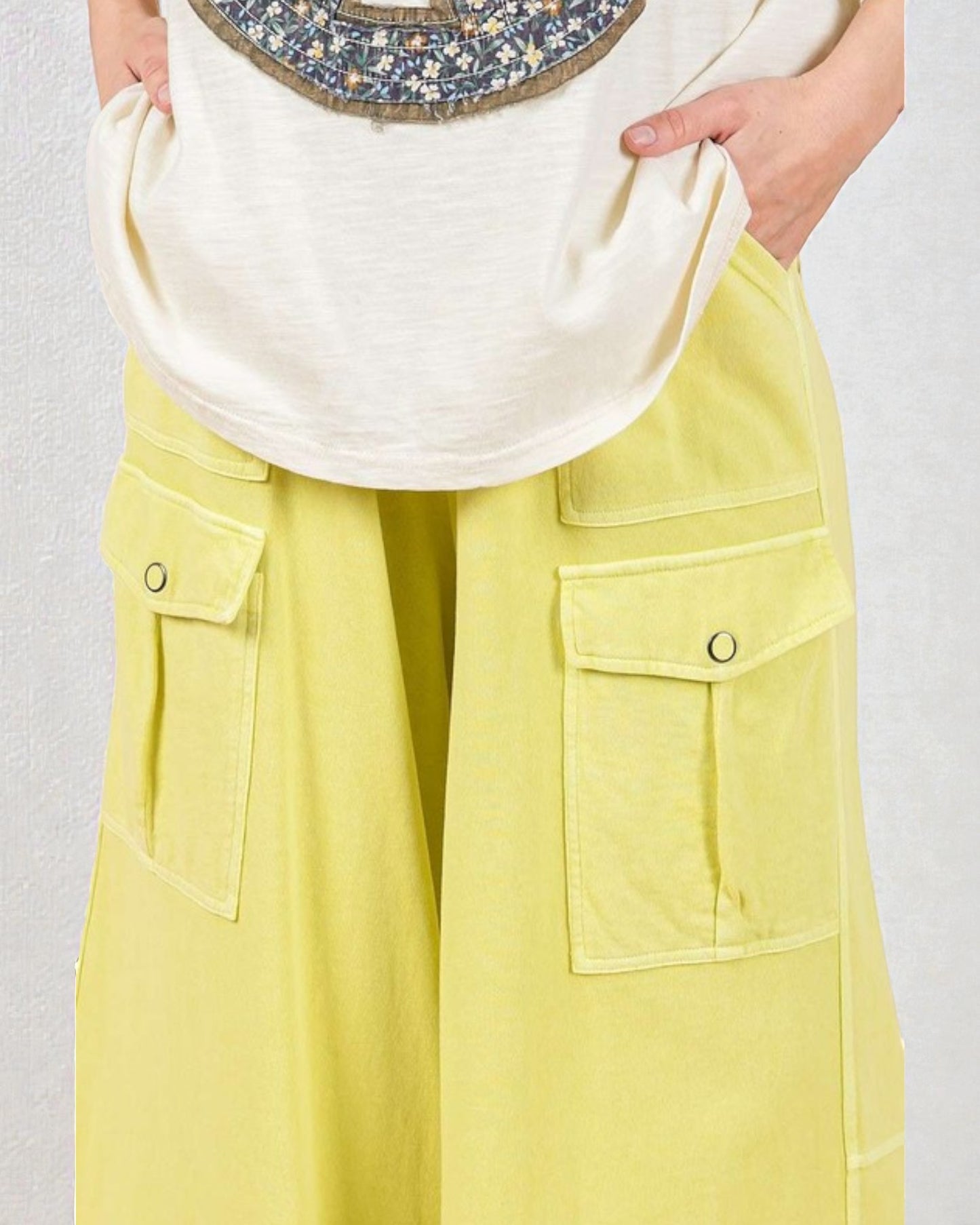 Person wearing a white top and yellow pants with a plain background