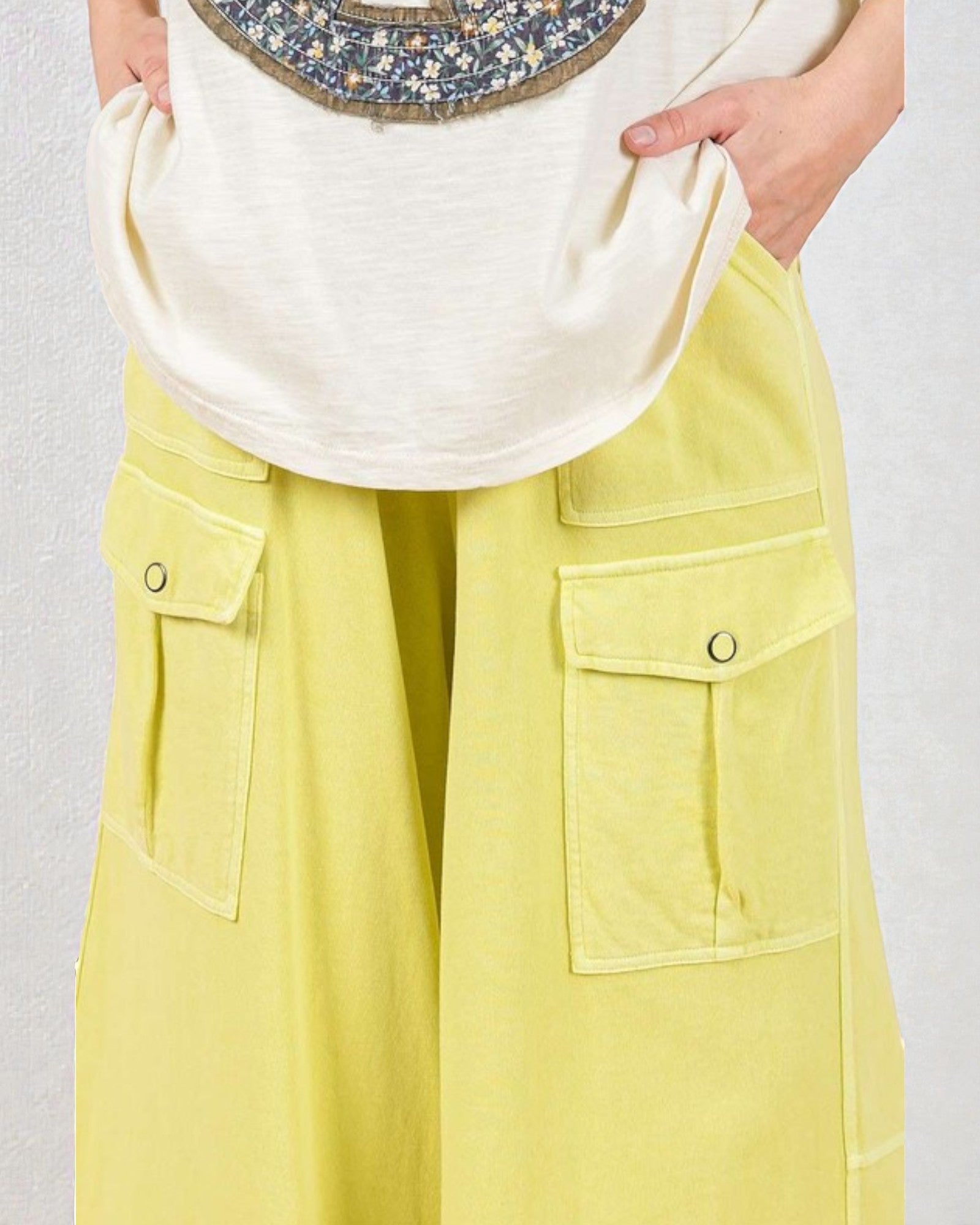 Person wearing a white top and yellow pants with a plain background