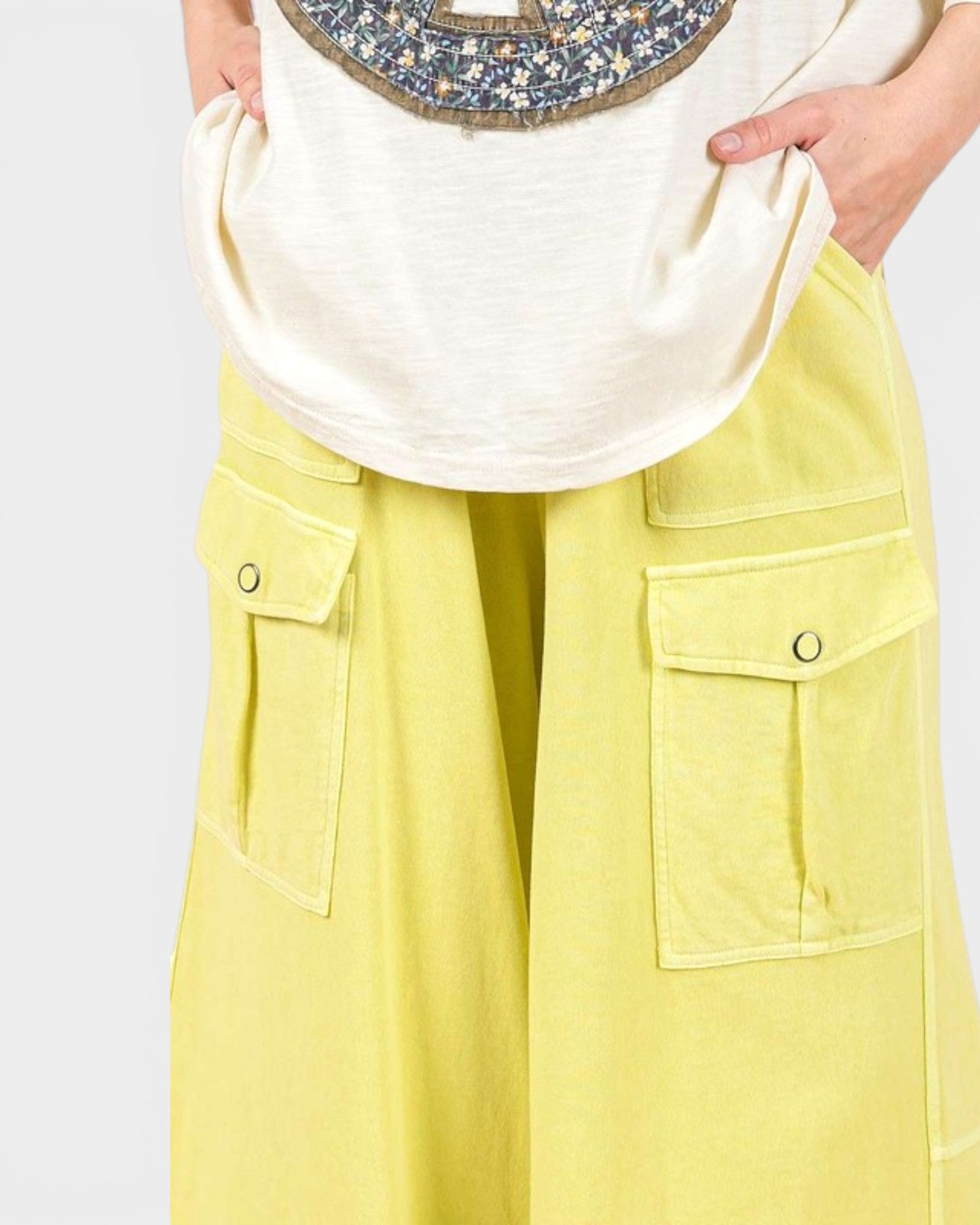 Person wearing a white shirt and yellow pants with a plain background
