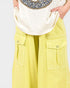 Person wearing a white shirt and yellow pants with a plain background