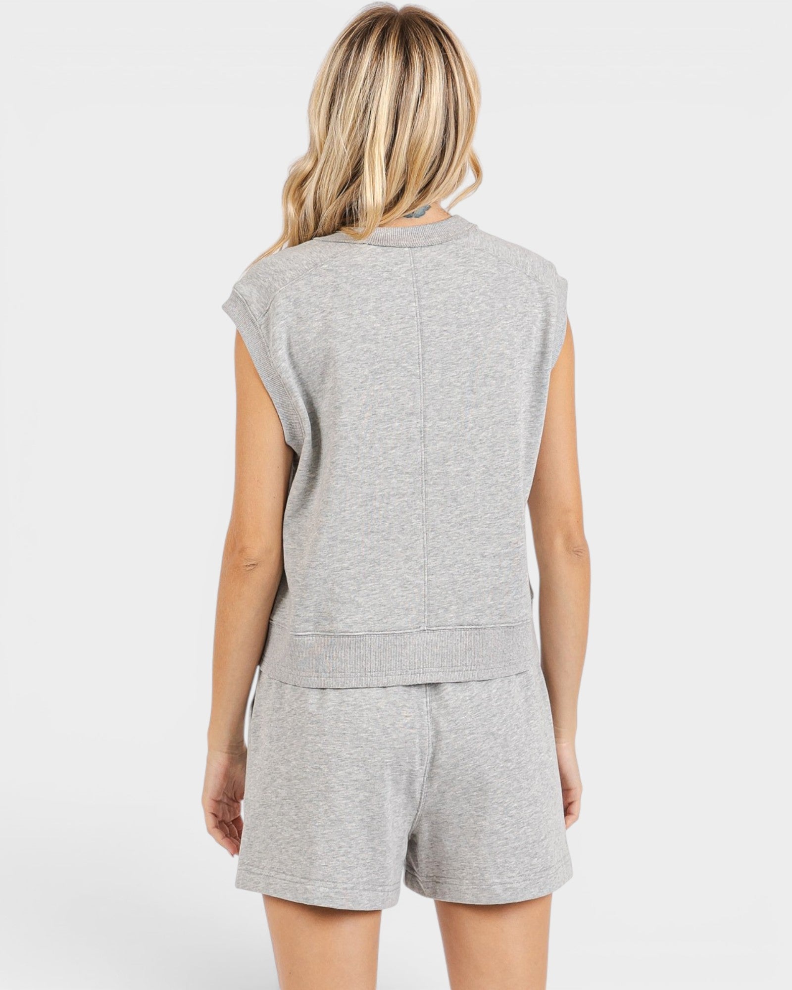Woman wearing a gray sleeveless top and shorts set on a white background