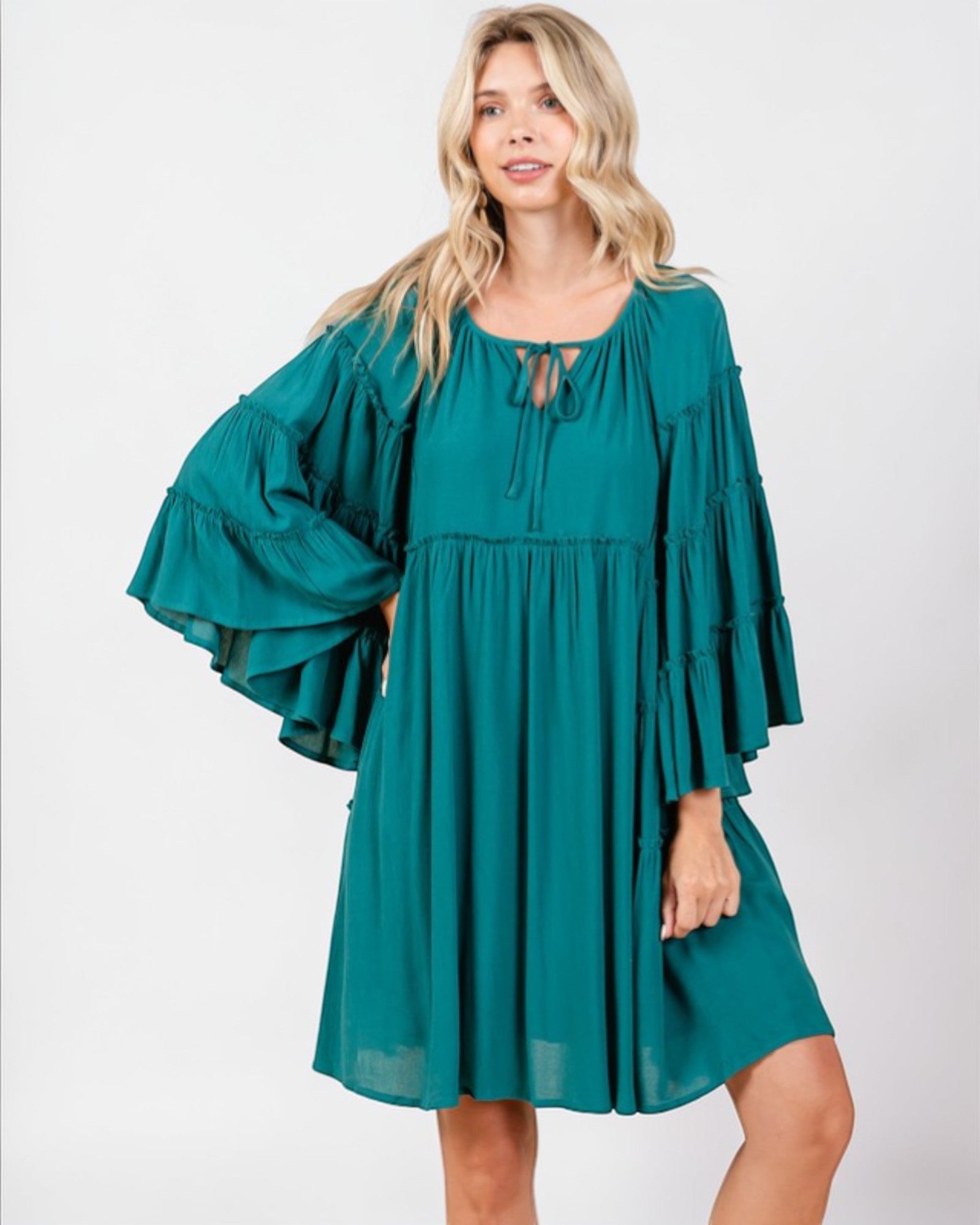 Woman wearing a teal dress with ruffled sleeves on a white background