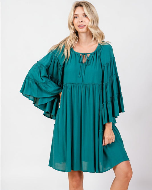 Woman wearing a teal dress with ruffled sleeves on a white background