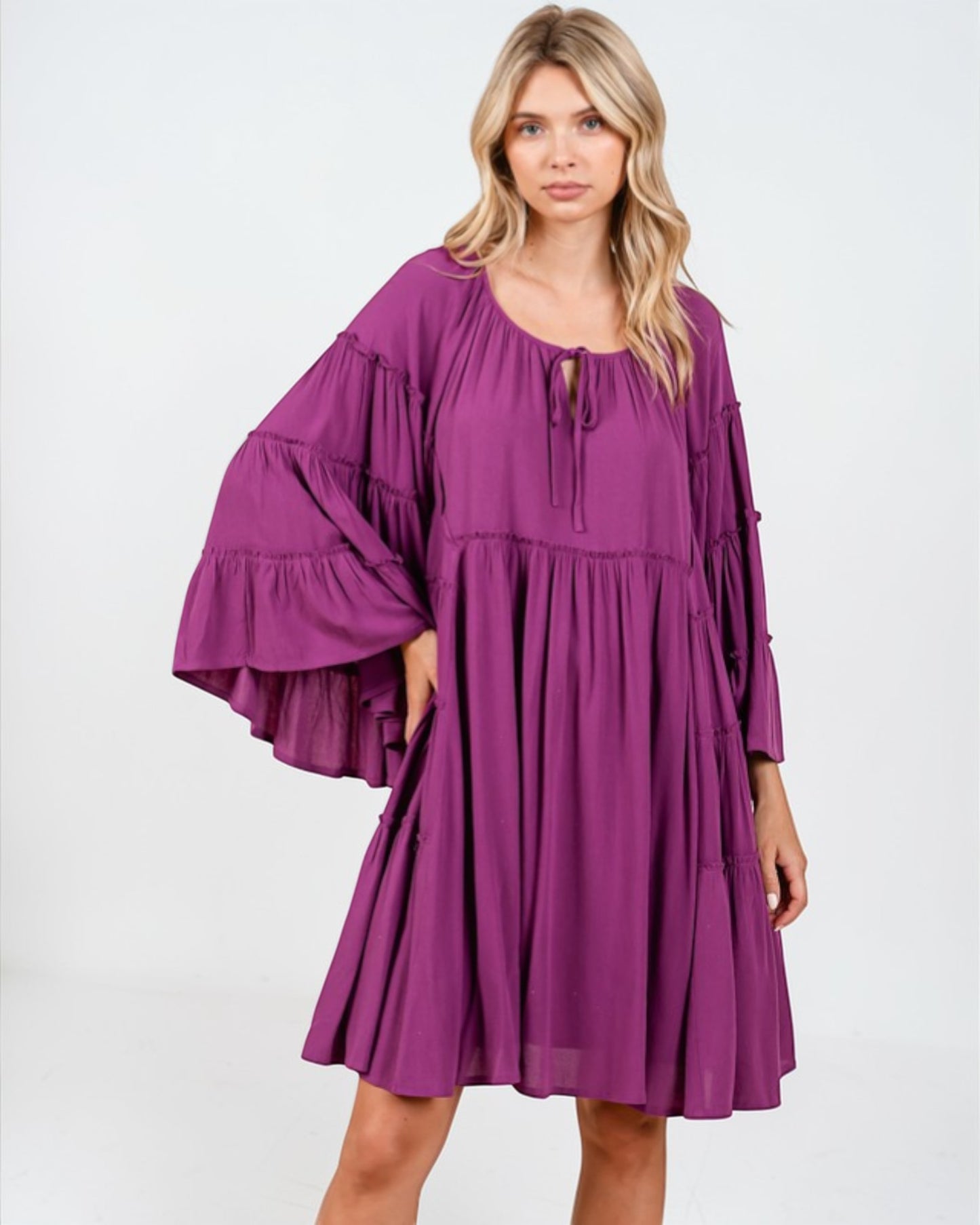 Woman wearing a purple dress with ruffled sleeves on a white background