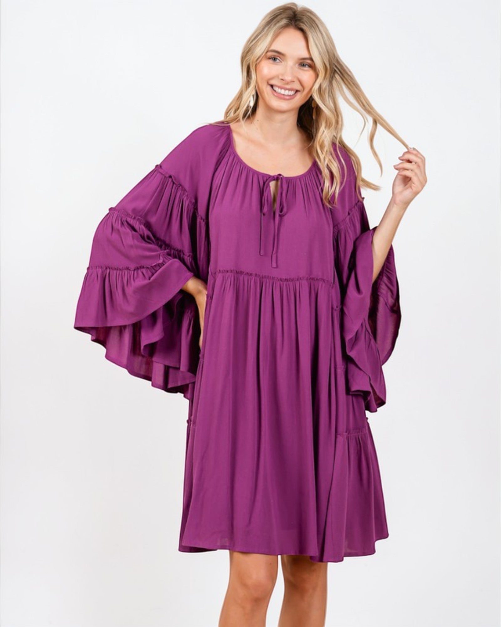 Woman wearing a purple dress with ruffled sleeves on a white background