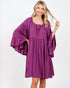 Woman wearing a purple dress with ruffled sleeves on a white background