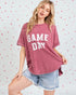 Woman wearing a 'GAME DAY' t-shirt with a heart-patterned background
