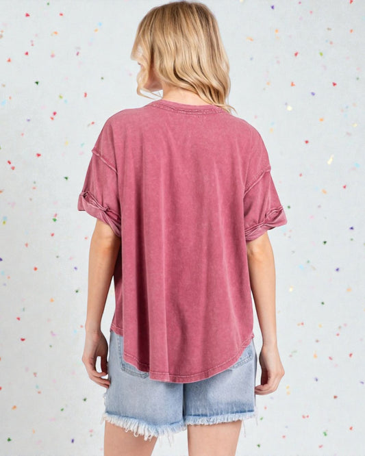 Person wearing a pink t-shirt and denim shorts against a colorful polka dot background