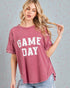 Woman wearing a maroon 'GAME DAY' t-shirt against a light gray background