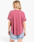 A woman shown from the back wearing a washed dusty rose short-sleeve t-shirt and light blue denim shorts against a plain white background.