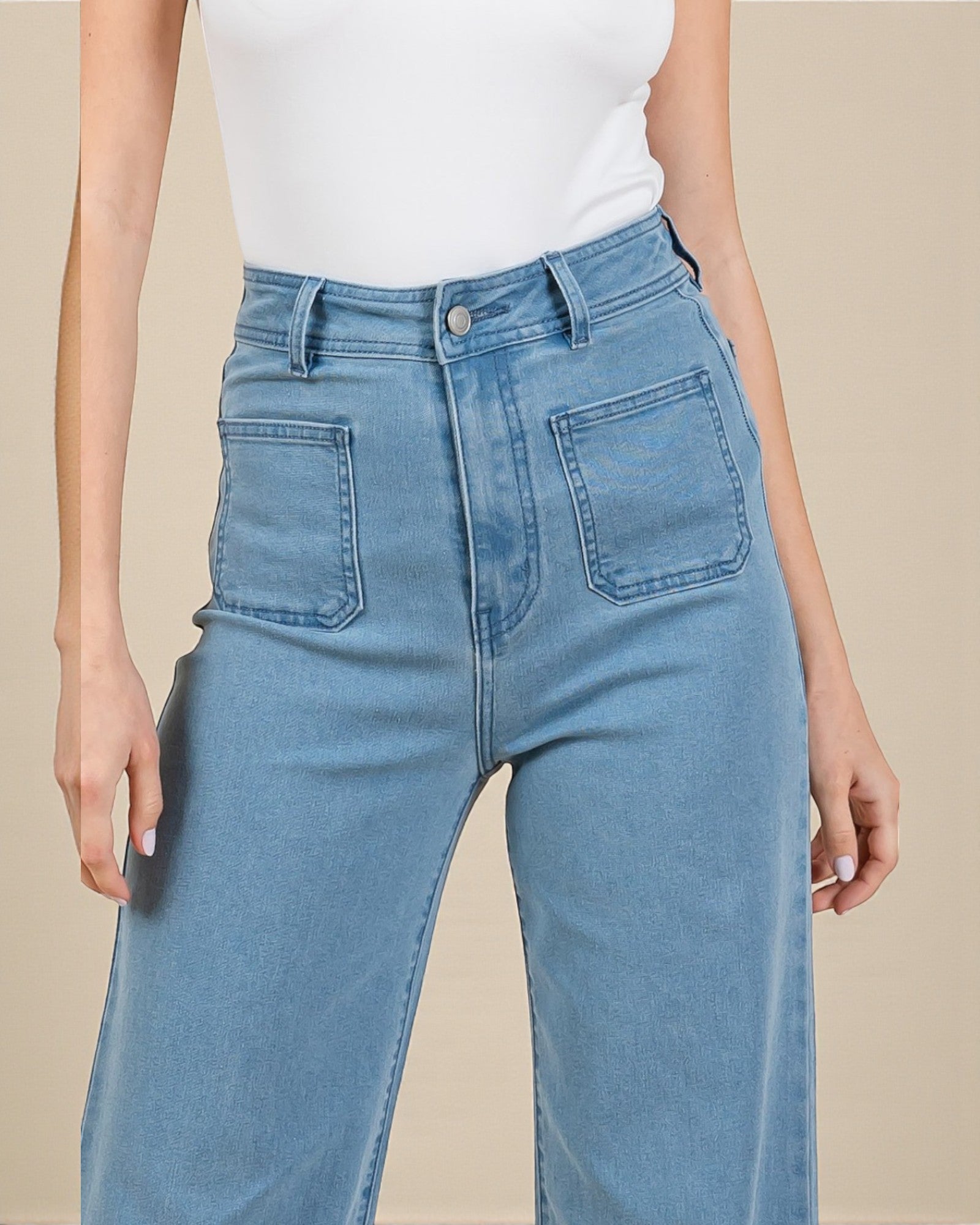 Light blue jeans worn by a person on a beige background