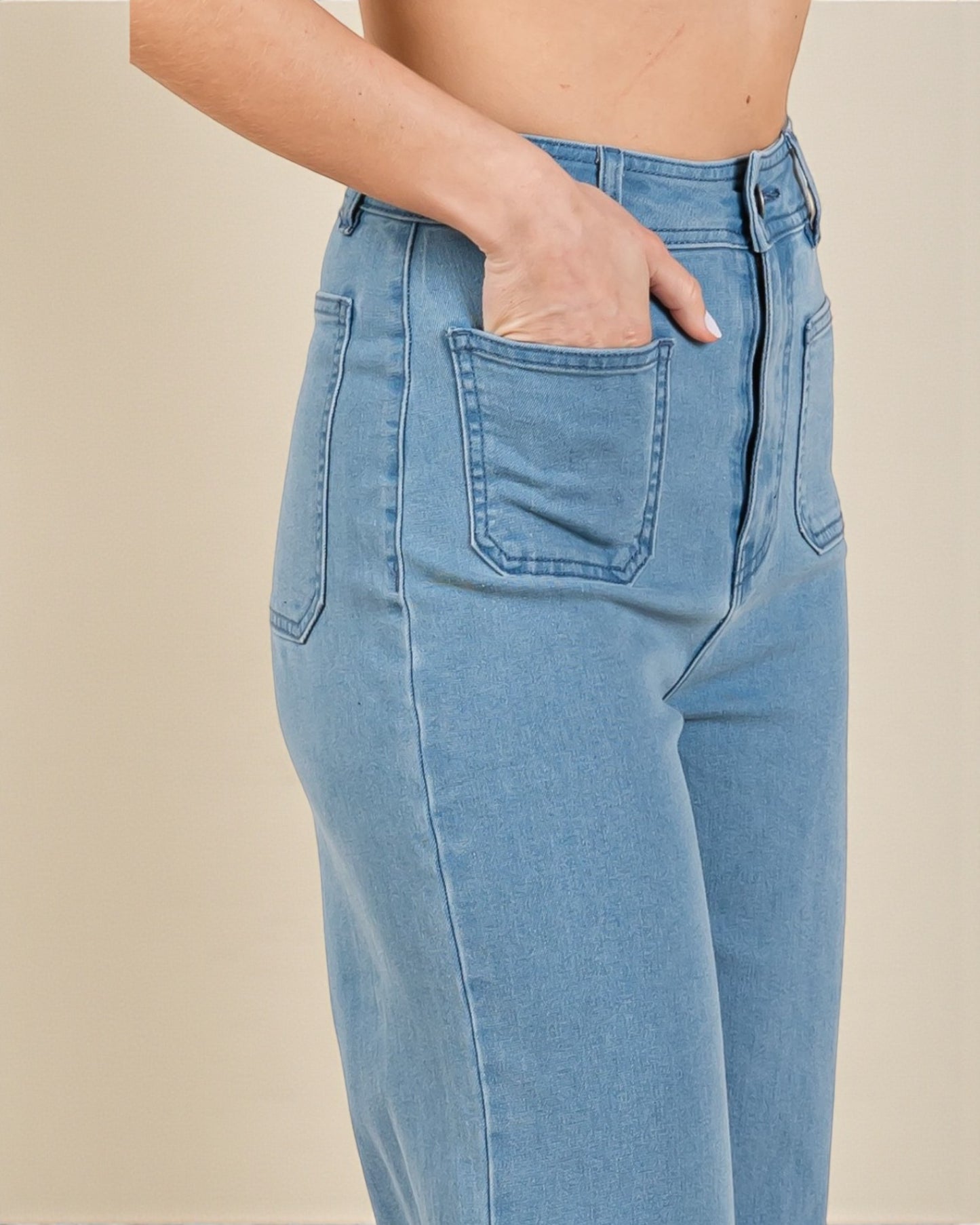 Light blue jeans worn by a person on a beige background