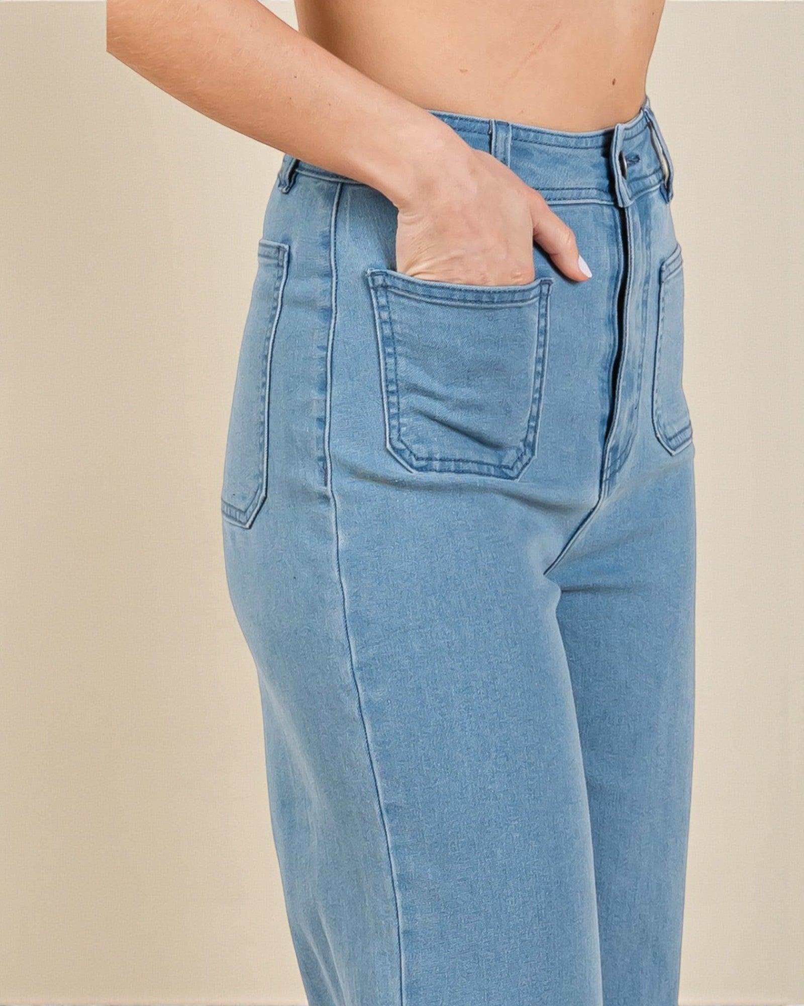 Light blue jeans worn by a person on a beige background