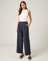 Woman wearing a white sleeveless top and navy wide-leg pants on a plain background
