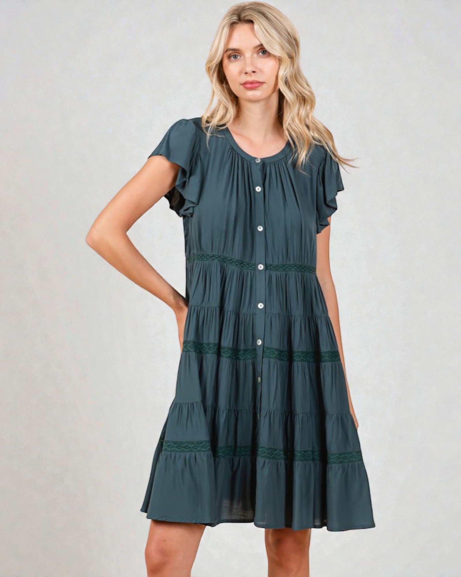 Woman wearing a green tiered dress on a plain background