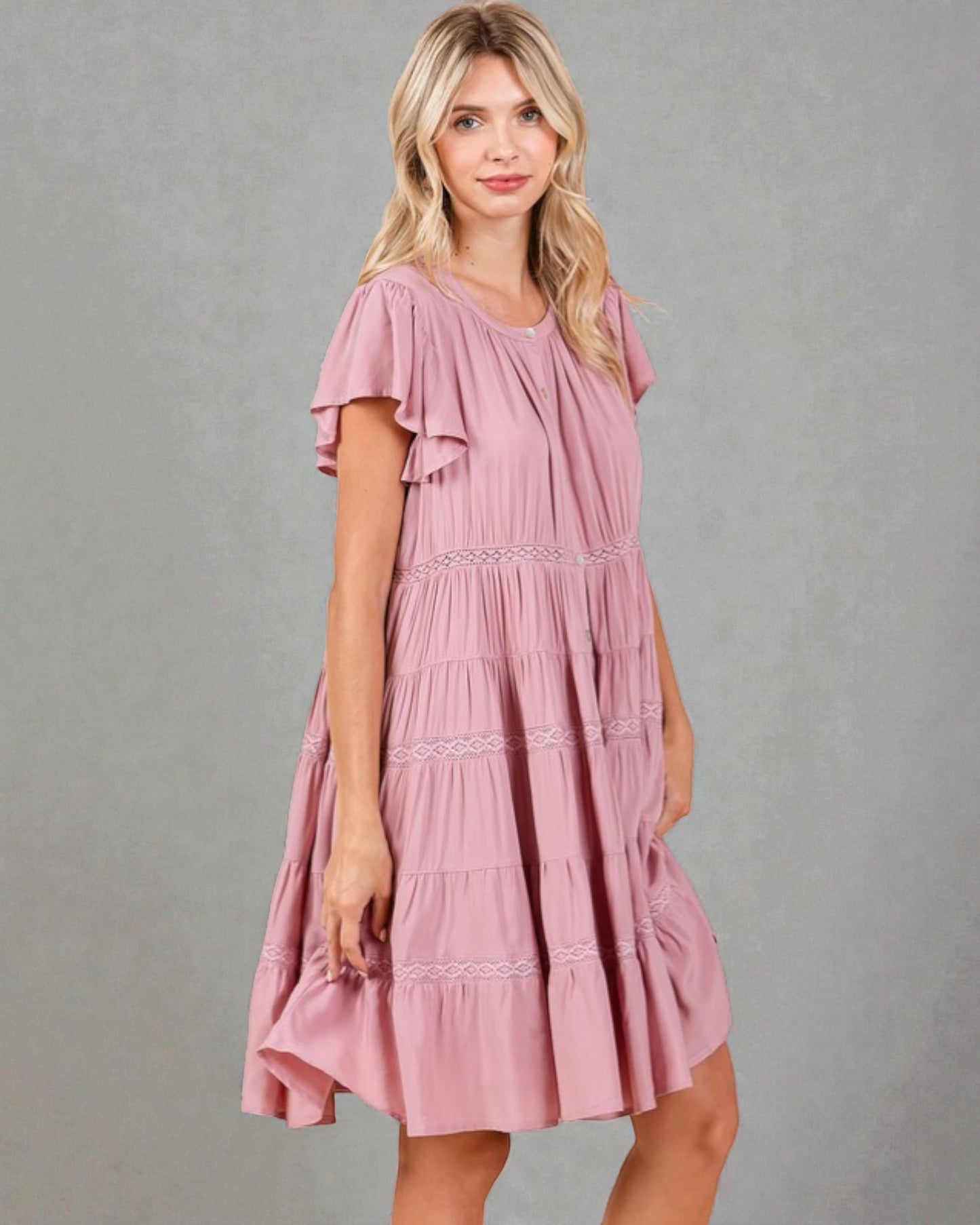 Woman wearing a pink dress against a gray background