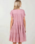 Pink tiered dress worn by a person on a white background