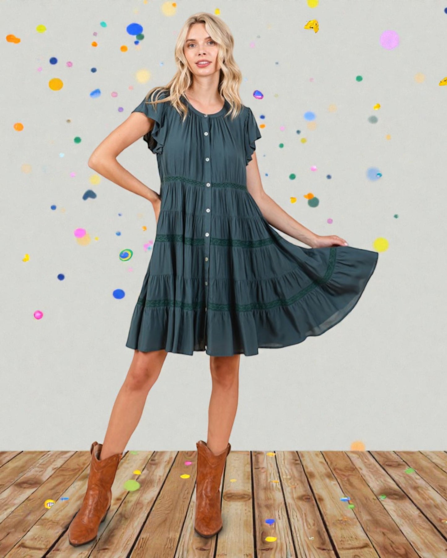 Woman wearing a green dress with brown boots on a wooden floor with colorful polka dots in the background