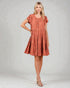 Woman wearing a rust-colored dress on a plain background