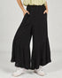 Person wearing black tiered wide-leg pants on a plain background
