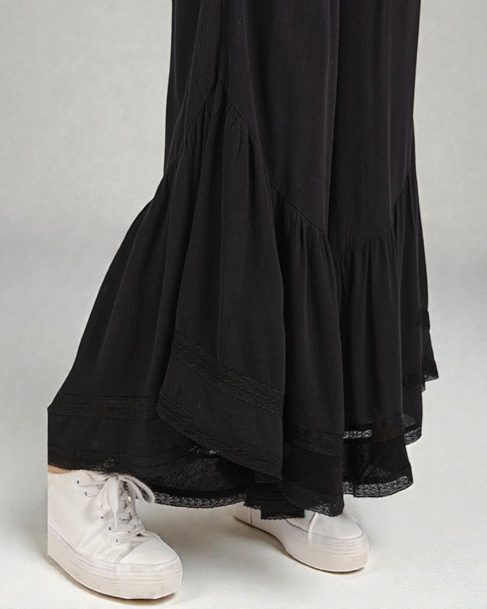 Black layered skirt worn with white sneakers on a plain background