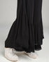 Black layered skirt worn with white sneakers on a plain background