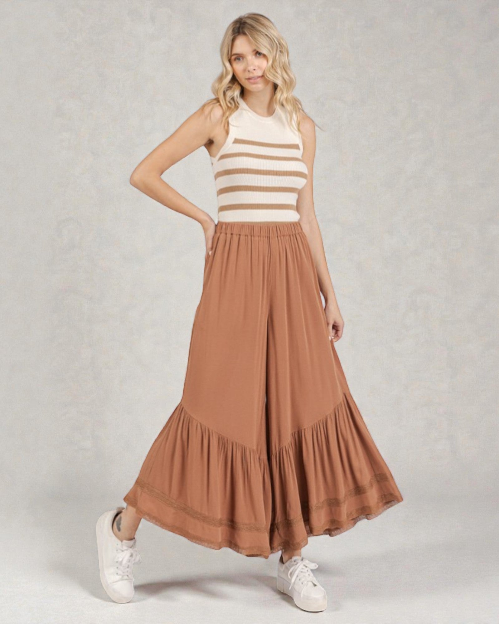 Woman wearing a striped top and brown skirt on a plain background