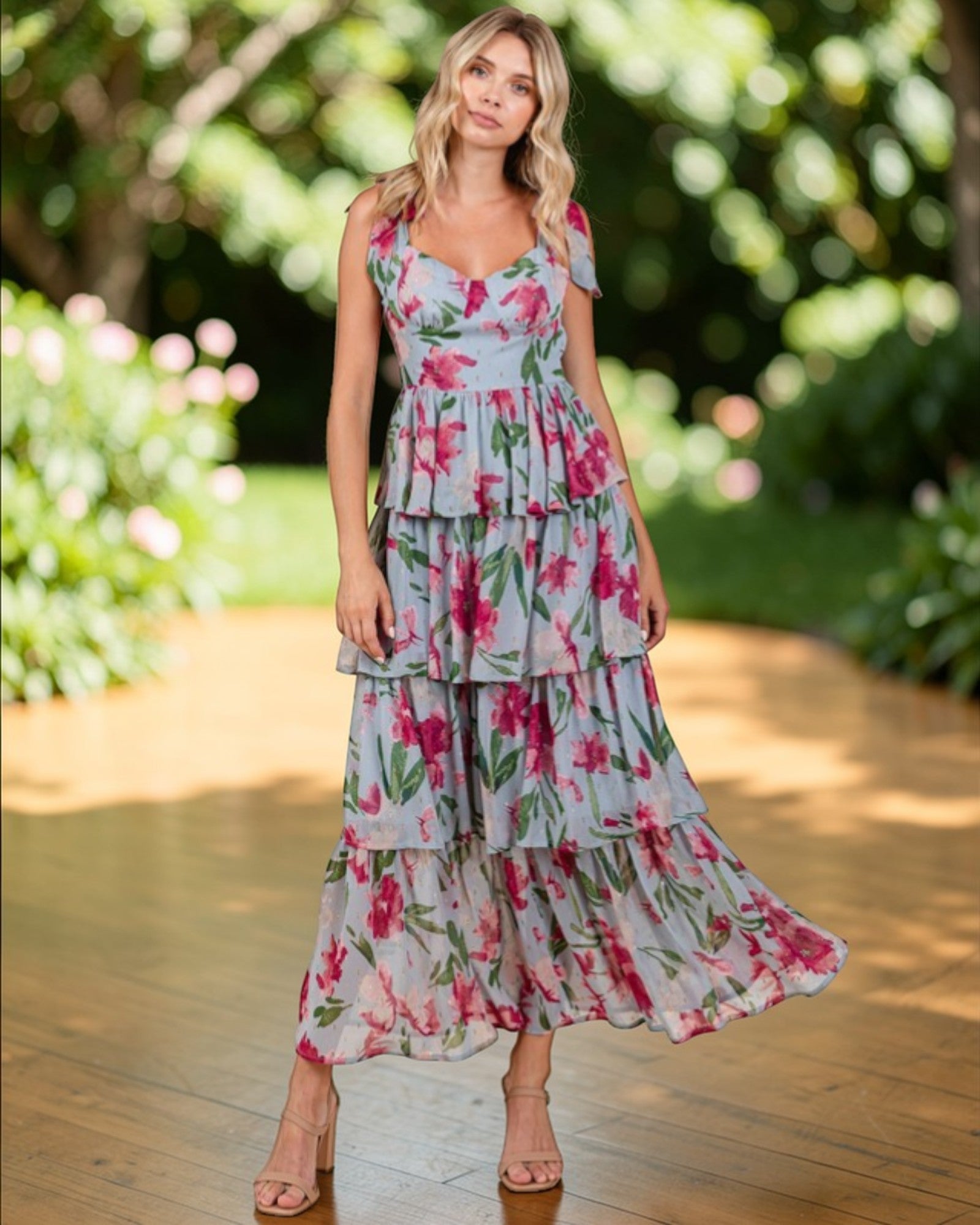 Woman wearing a floral dress standing outdoors with greenery in the background