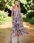 Woman wearing a floral dress standing outdoors with greenery in the background