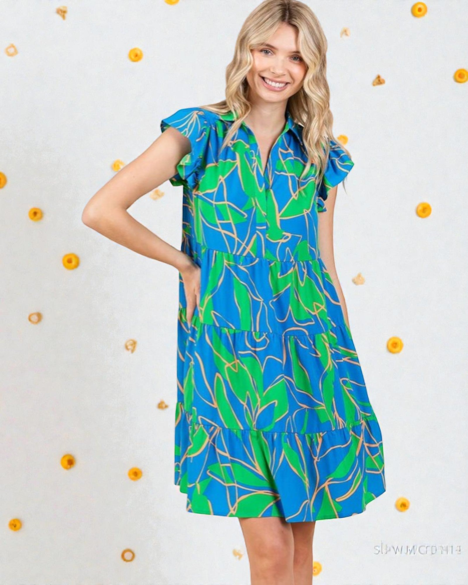 Woman wearing a blue and green patterned dress against a light background with small decorative elements.