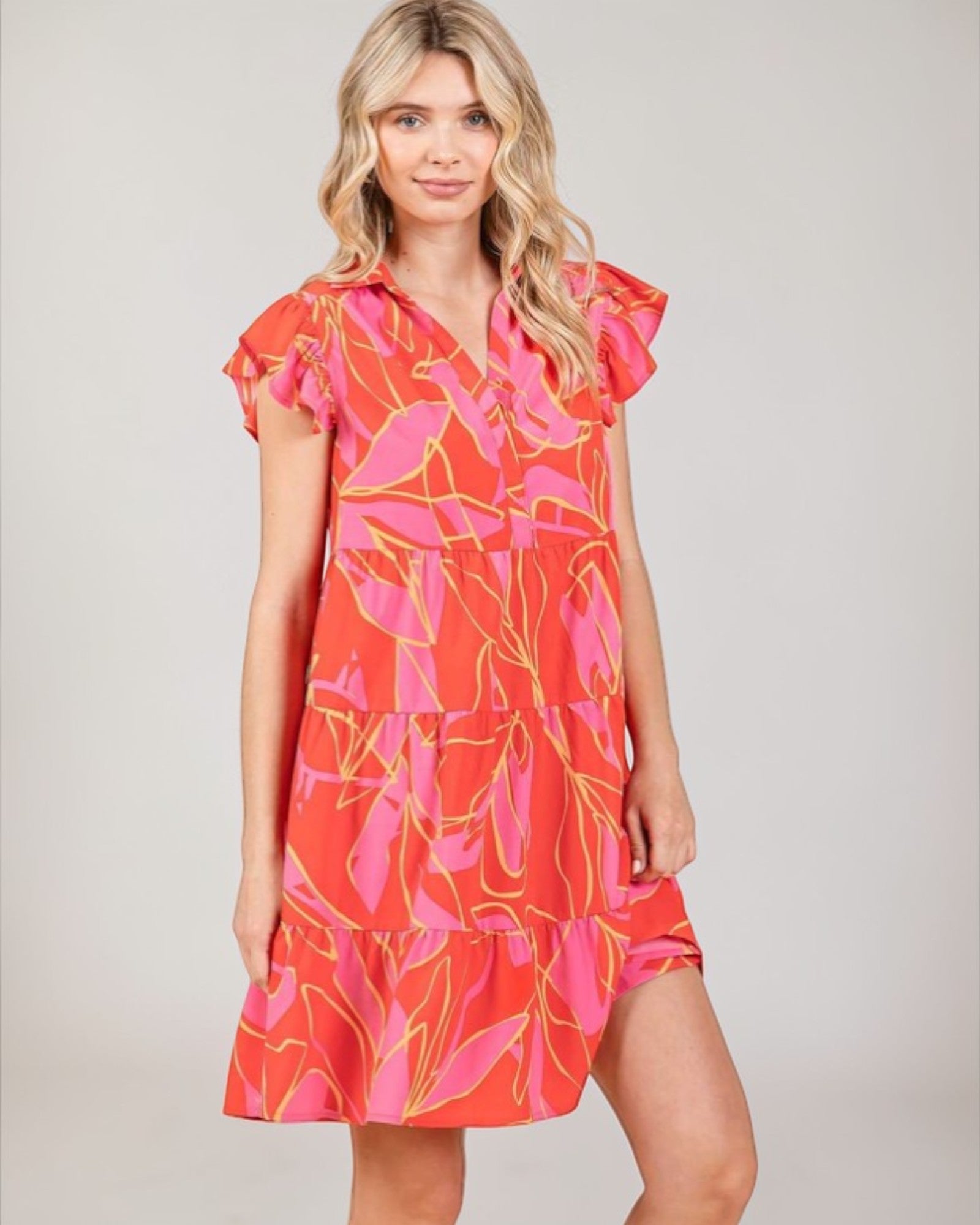 Woman wearing a colorful dress with a pattern on a plain background