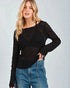 Woman wearing a black textured sweater and blue jeans against a light gray background