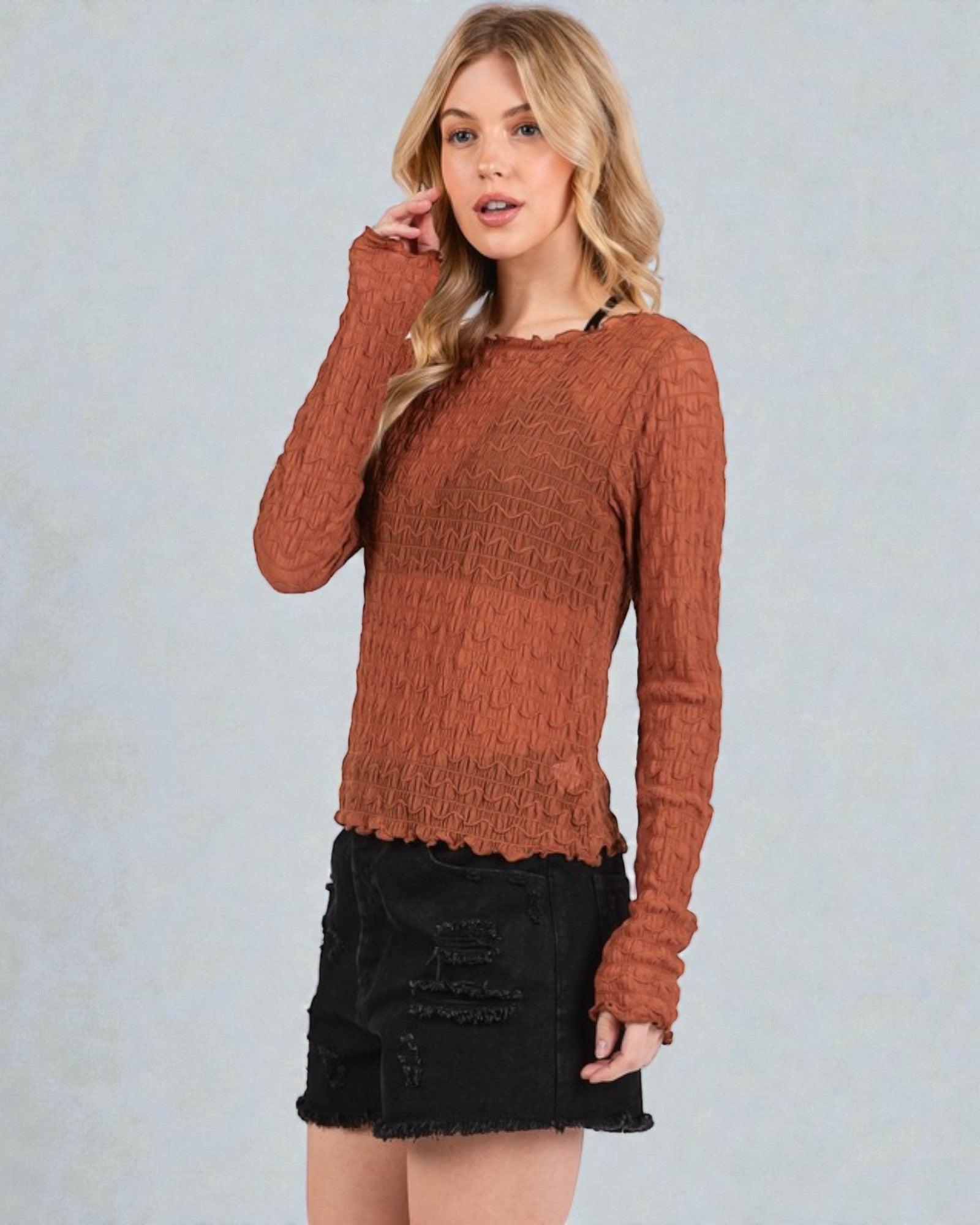 Woman wearing a brown sweater and black skirt against a light gray background