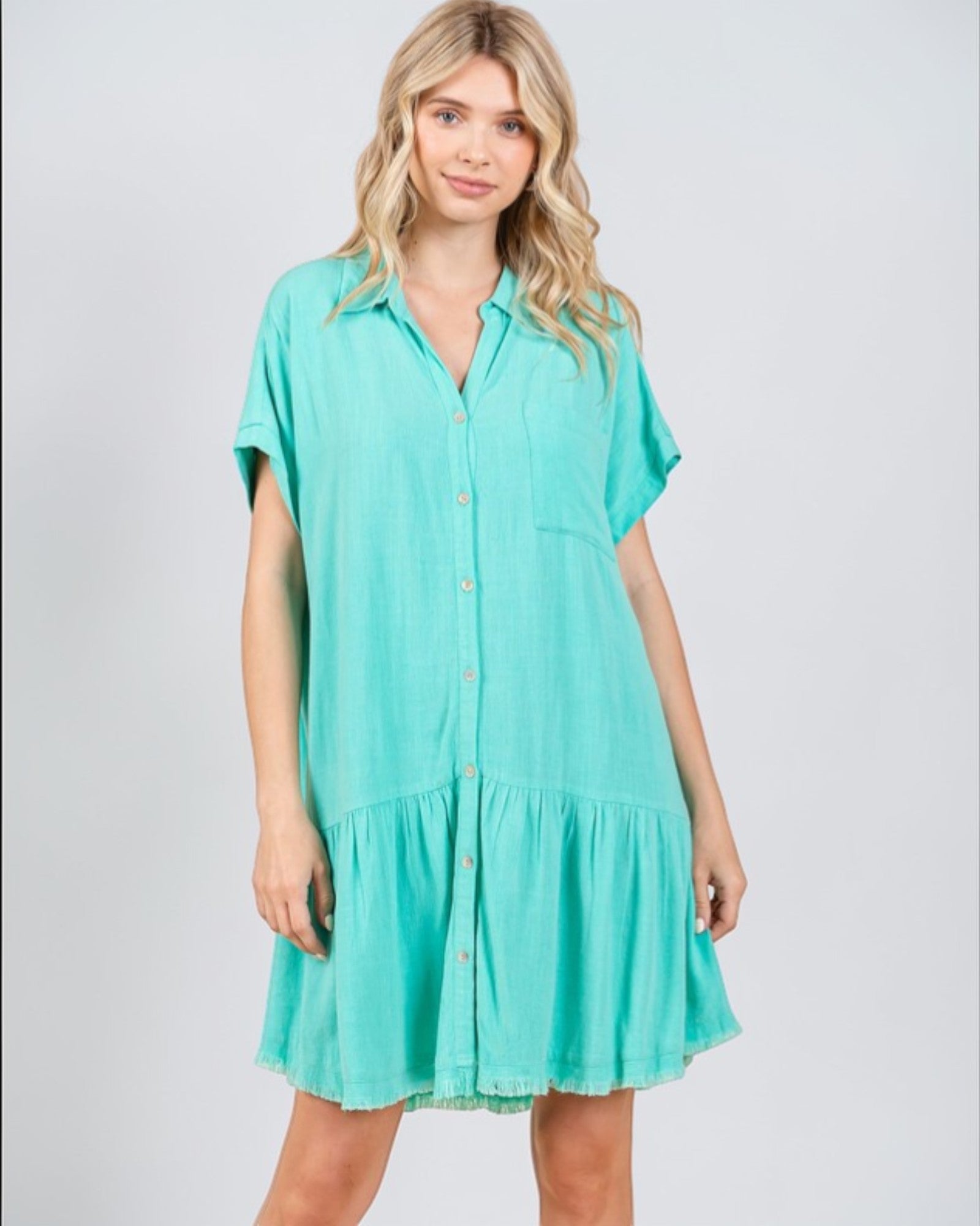 Woman wearing a teal dress on a plain background