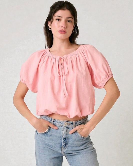 Woman wearing a pink blouse and blue jeans against a plain background