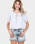 Woman wearing a white blouse and denim shorts on a plain background