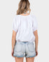 Person wearing a white blouse and denim shorts on a plain background