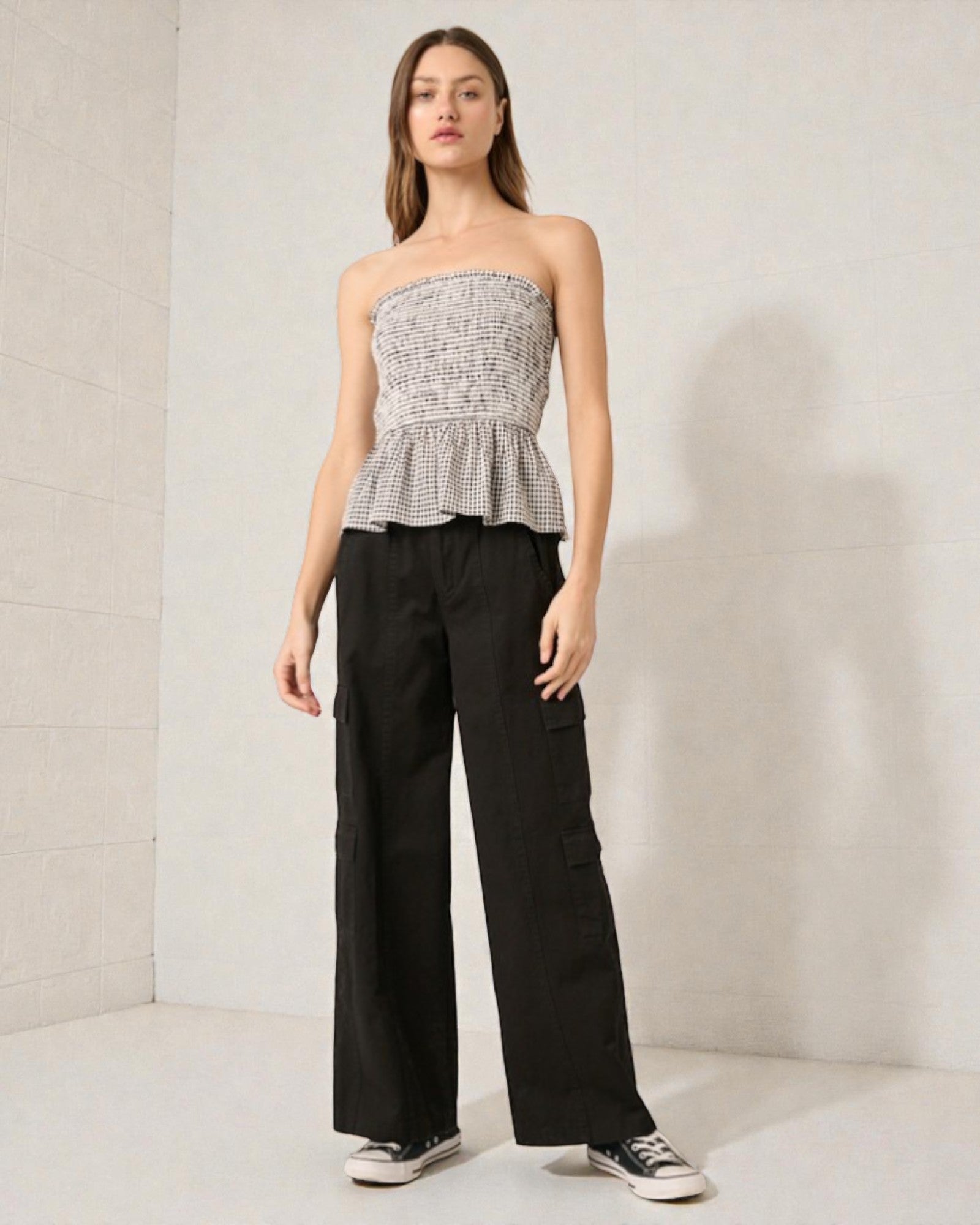 Woman wearing a strapless top and black pants against a plain background