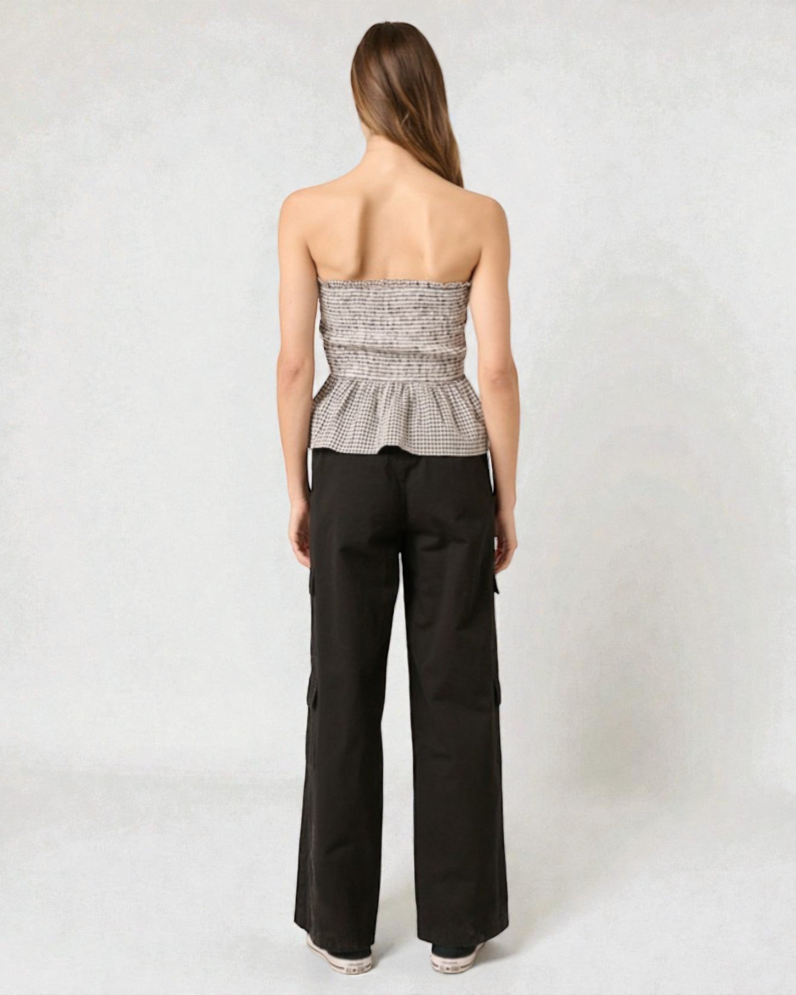 Woman wearing a strapless top and black pants on a white background