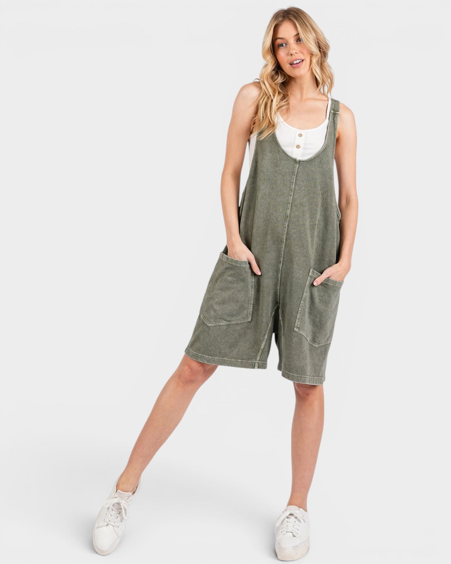 Woman wearing a green overalls dress on a white background