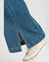 Close-up of blue jeans with a white sneaker on a light gray background