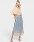 Woman wearing a beige top and blue patterned skirt on a white background