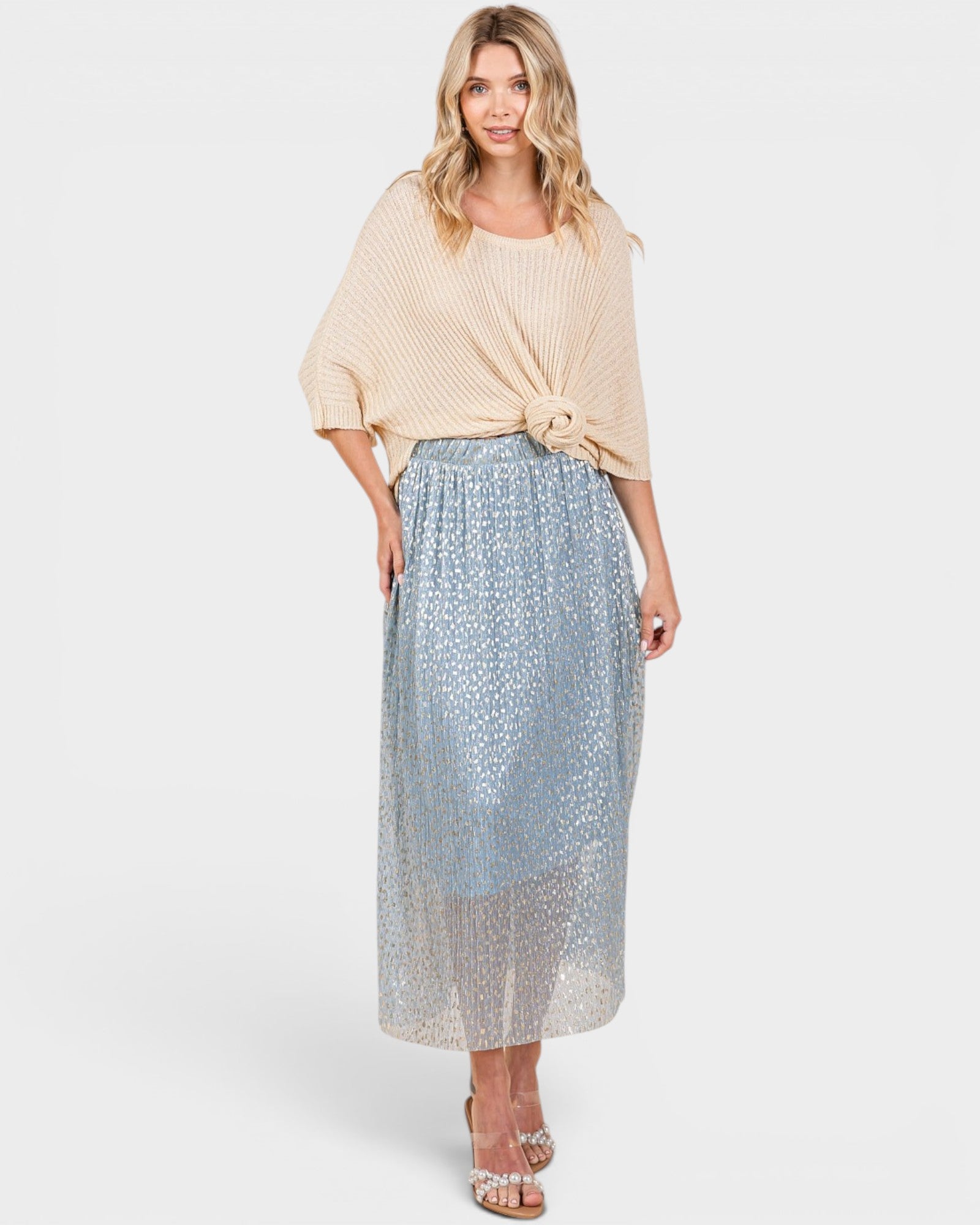 Woman wearing a beige top and patterned skirt on a white background