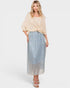Woman wearing a beige top and patterned skirt on a white background