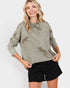 Woman wearing a green sweater with embroidered designs on a white background