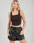 Woman wearing a black sleeveless top and shorts on a gray background