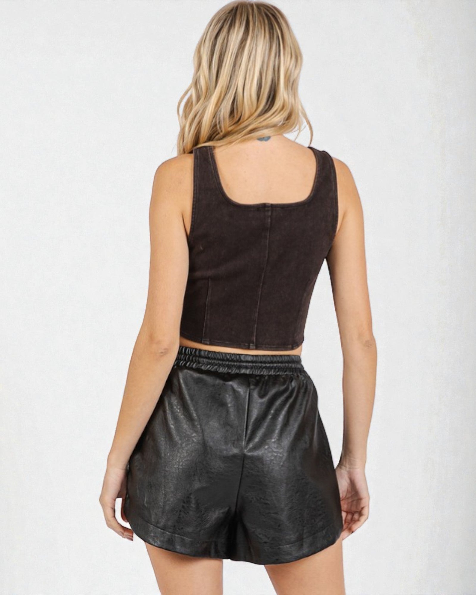 Woman wearing a brown top and black leather shorts on a white background