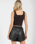 Woman wearing a brown top and black leather shorts on a white background