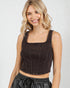 Woman wearing a black sleeveless top against a plain background