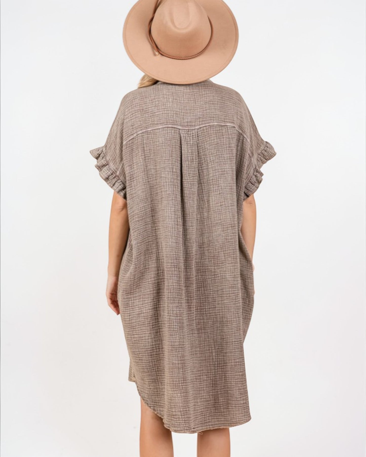 Person wearing a brown checkered dress with ruffled sleeves on a white background